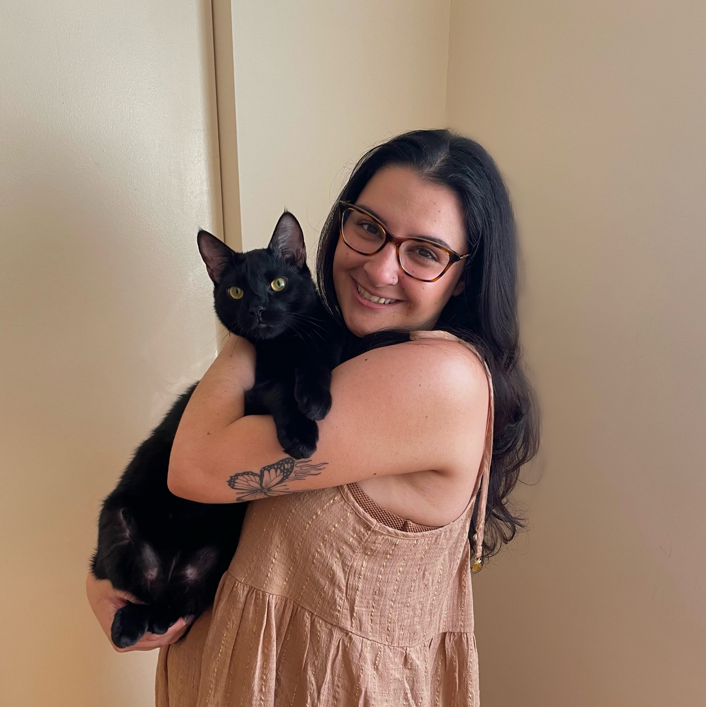 Smiling woman holding a black cat in her arms.