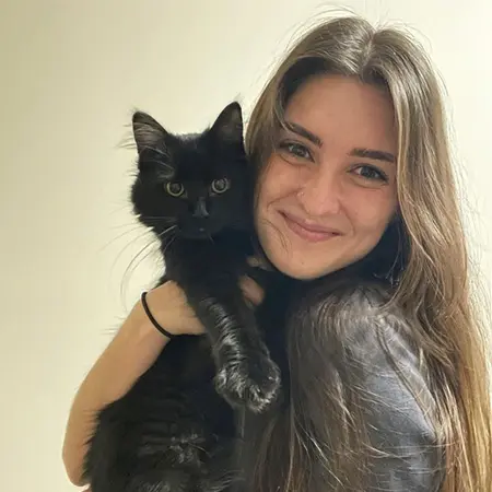 Woman smiling while holding a black cat.