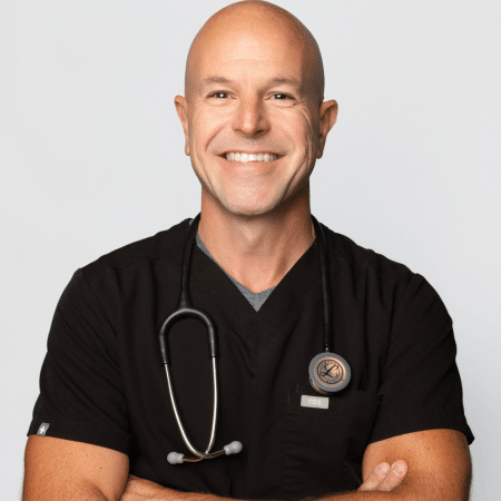 Dr. Nicholas Spaccarelli smiling in black scrubs with a stethoscope around his neck, arms crossed.